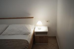 a bedroom with a bed and a nightstand with a lamp at OLIVE in Nerezine