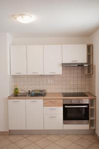 a kitchen with white cabinets and a sink at OLIVE in Nerezine +11 photos