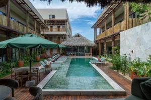 a pool with chairs and umbrellas next to a building at Be caju flats in Barra Grande