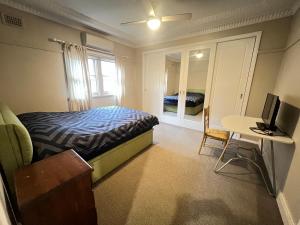a bedroom with a bed and a desk with a television at Room 73 in Merrylands
