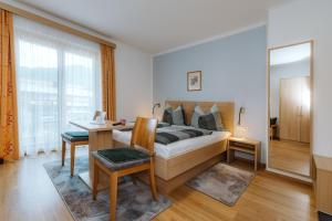 a bedroom with a bed and a desk and a window at Haus Lackner am Weissensee in Kärnten in Weissensee