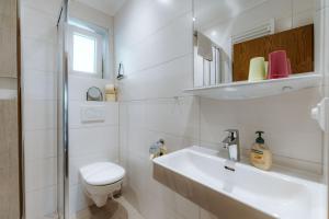 a white bathroom with a toilet and a sink at Haus Lackner am Weissensee in Kärnten in Weissensee