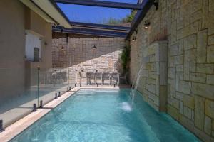 a swimming pool in a building with a stone wall at Villa Lausanne - View in Dāliyat el Karmil