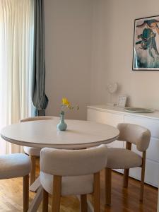 a dining room table with chairs and a vase with flowers at Sunshine Residence in Stara Baška