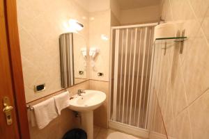 uma casa de banho com um lavatório e um chuveiro com um espelho. em Hotel Zara Napoli em Nápoles