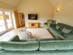 a living room with two green couches and a tv at Bobblehat Barn in Alford