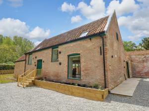 a brick building with a door and a fence at Bobblehat Barn in Alford