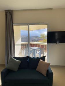 a living room with a couch and a balcony with a table at Chalet 102 - Zresidence - Faitroun in Al ‘Aqabah