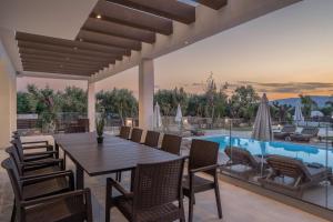 an outdoor dining area with a table and chairs and a pool at Villa V - Infinity Holiday Villas, For Large Groups With Private Pool, by ZanteWize in Kalamaki +35 photos