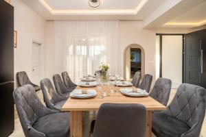 a dining room with a wooden table and chairs at Villa V - Infinity Holiday Villas, For Large Groups With Private Pool, by ZanteWize in Kalamaki