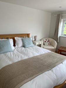 a bedroom with a large white bed and a chair at Gorse cottage in Newton Abbot