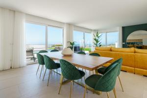 a dining room with a wooden table and green chairs at Casa Caracol, with a panoramic ocean view in Lourinhã +34 photos
