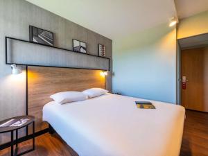 a bedroom with a large white bed in a room at ibis Besançon Marchaux in Marchaux