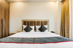 a bedroom with a large white bed with pillows at Super Townhouse MA-32 in Gurgaon