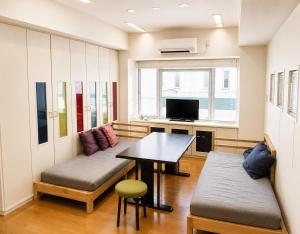 a room with two benches and a table and a tv at The Little Kamakura Hotel 鎌倉駅徒歩2分 in Kamakura