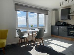 a kitchen with a table and chairs in a room at Harbour Point Apartment in Saltcoats