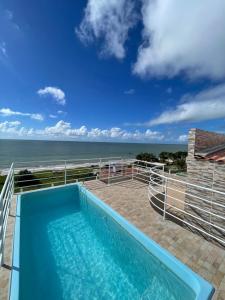 a swimming pool with a view of the ocean at Apartamento Frente Mar in Jacumã