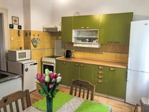 a kitchen with green cabinets and a table with a vase of flowers at Villa Forestside Villa by Interhome in Planá nad Lužnicí