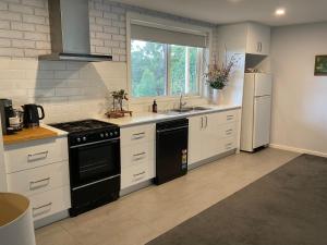 a kitchen with white cabinets and a black stove top oven at Bruny Sunset Beach in Alonnah +23 photos