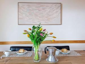 a vase of flowers sitting on a table with plates at Apartment Apt-Woka by Interhome in Aldesago
