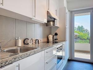 a white kitchen with a sink and a window at Apartment Apt-Woka by Interhome in Aldesago