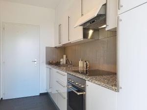 a kitchen with white cabinets and a stove top oven at Apartment Apt-Woka by Interhome in Aldesago +13 photos
