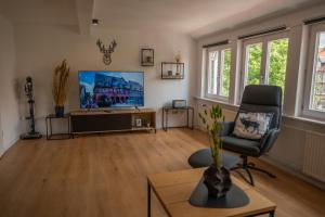 a living room with a chair and a television at Goslar LIVING 1 - Modern & Zentral in Goslar
