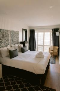 a large white bed in a room with a large window at The Hamptons Beach House in East Preston