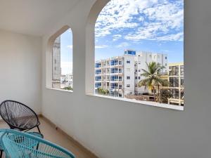 a room with two windows and a chair and a palm tree at Le Lodge des Almadies in Dakar