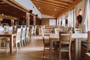a dining room with wooden tables and white chairs at Grmovškov dom Kope in Mislinja