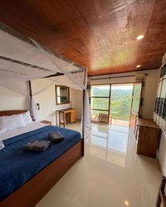 a bedroom with a bed and a large window at Rainforest mountain resort in Deniyaya