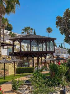 a large wooden pavilion in a park with palm trees at Bungalows Imperial Park Unitursa in Calpe