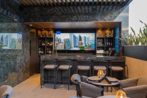 a bar with stools and a flat screen tv at Punto Suites Periférico Sur in Mexico City