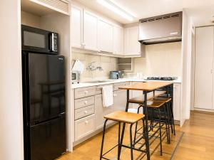 a kitchen with a black refrigerator and a table with stools at The Little Kamakura Hotel 鎌倉駅徒歩2分 in Kamakura