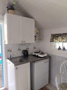 a small kitchen with white cabinets and a sink at The little cottage in Saltvik
