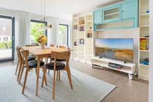 a dining room with a table and a tv at Fischerhus Laboe in Laboe