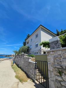 a building on the beach next to a stone wall at Villa Lovorka by VILLA EVA in Omišalj