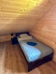 a bed in a room with a wooden wall at Chatki Bies-Czadowe-Bies in Berezka