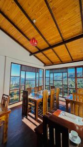a dining room with tables and chairs and windows at travellers nest inn in Nuwara Eliya