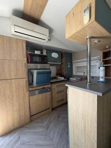 a kitchen with wooden cabinets and a counter top at Chez Yoyo Mobil-home tout confort pour des vacances inoubliables in Saint-Raphaël +11 photos