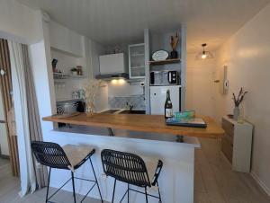 a kitchen with a counter with two chairs and a table at Le Studio Fouesnantais in Fouesnant +22 photos