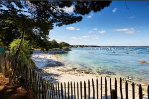 a fence on a beach with boats in the water at Le Studio Fouesnantais in Fouesnant