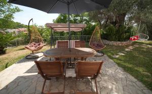 a wooden table with chairs and an umbrella at Vila Brca in Brca