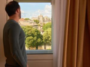 a man looking out a window at a city at ibis Avignon Centre Gare in Avignon