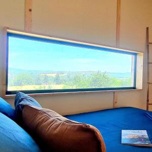 a large window in a room with a bed in front at Les nids de Bonnan in Milhars