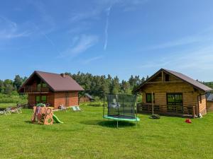 a log cabin with a playground and a chair in the yard at Chatki Bies-Czadowe-Bies in Berezka