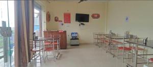 a room with tables and chairs in a room with a tv at Heera Hotel& Restaurant in Gupta Kāshi
