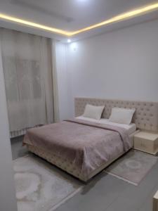a bedroom with a large bed in a white room at Mina appartement in Ariana