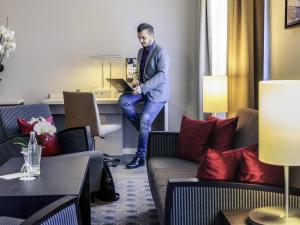 a man standing in a room with a laptop at Mercure Hotel München Süd Messe in Munich