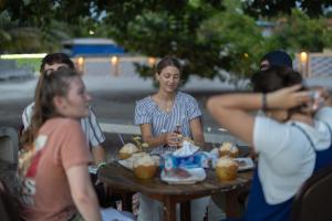 Eine Gruppe von Menschen sitzt an einem Tisch und isst Essen in der Unterkunft Dhonveli Hotel in Shaviyani Atoll